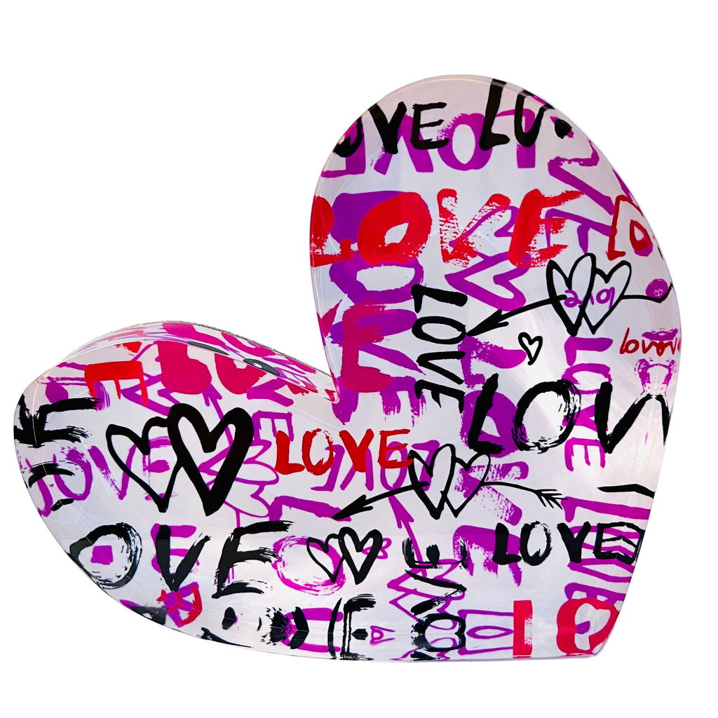 An acrylic heart-shaped block with a graffiti-style pattern of the words 'love' in various colors.