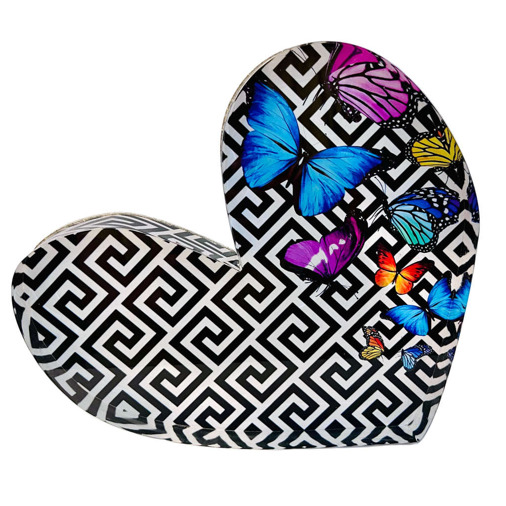 Acrylic heart-shaped block with a geometric pattern and colorful butterfly designs on it.