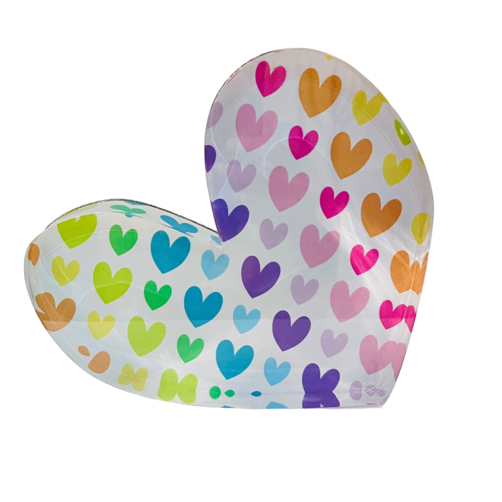 A freestanding, heart-shaped acrylic block with a multicolored pattern of hearts on it.