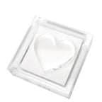 Clear heart-shaped object in a transparent lucite napkin holder