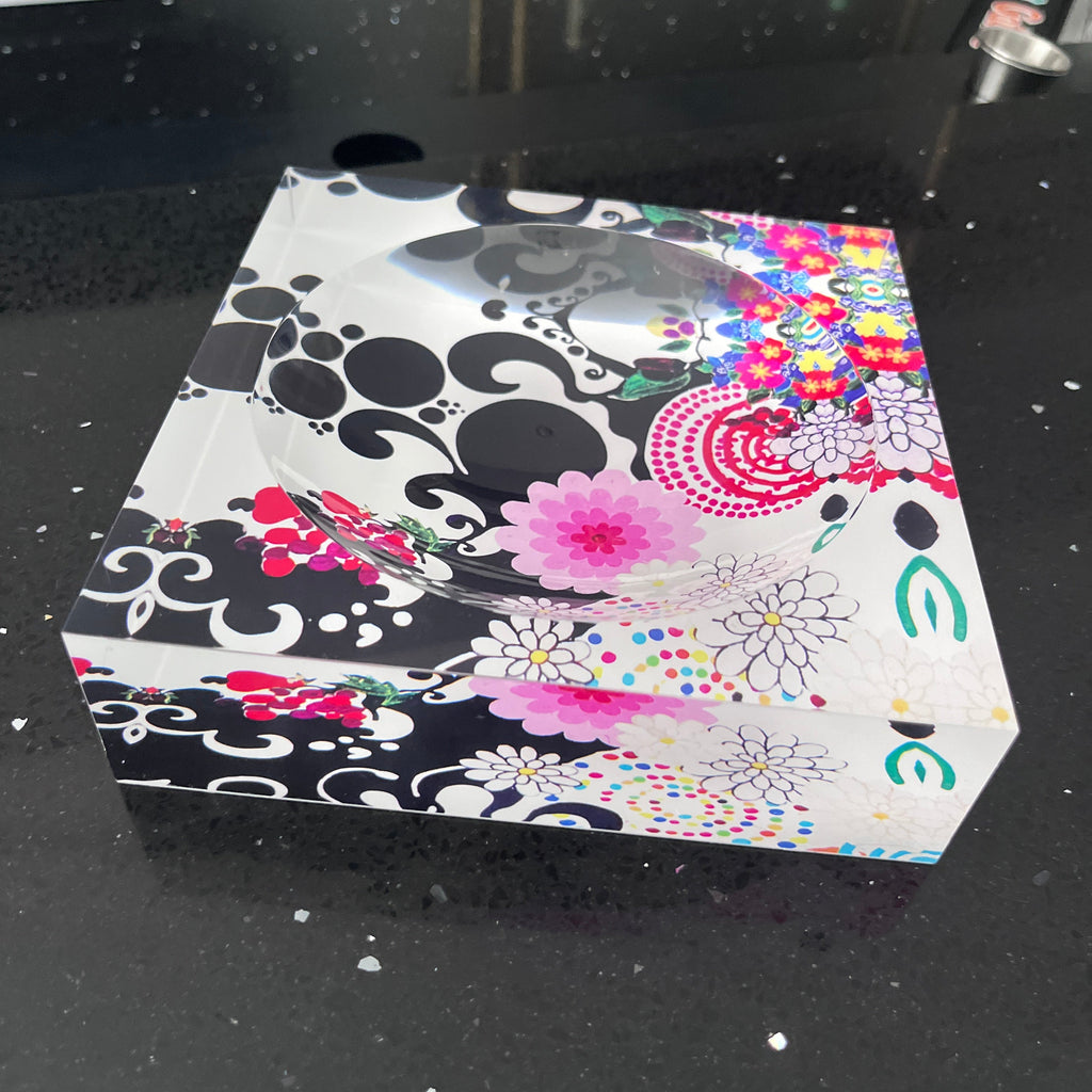 Decorative acrylic candy dish with floral and abstract patterns on a black background