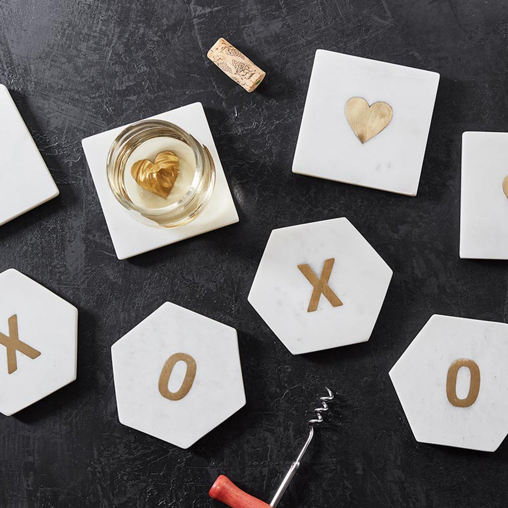 Hexagonal marble coasters with gold letters and heart design on a dark surface.