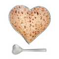 A heart-shaped aluminum bowl with a textured pattern resembling matzah, accompanied by a matching heart-shaped spoon, against a black background.